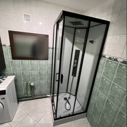 Łazienka z czarną kabiną prysznicową i pralką — DobryHydraulik Bydgoszcz